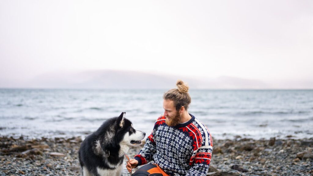 Man Sitting on a Seashore with His Husky Dog